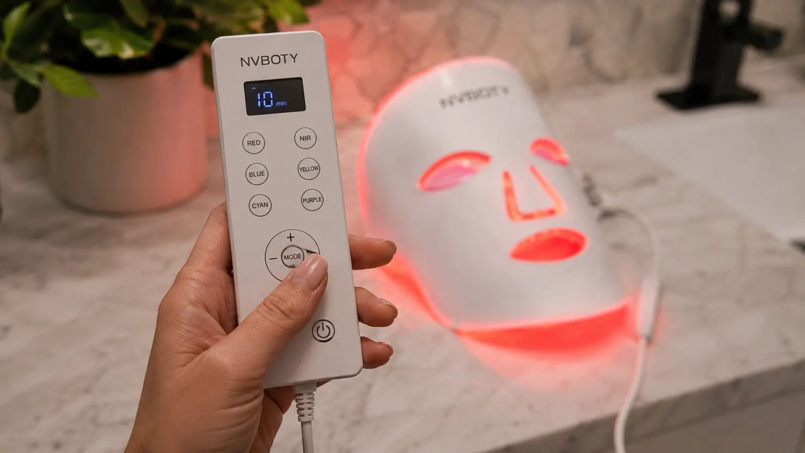 Close-up of hand holding the NVBOTY mask remote to select the red light mode