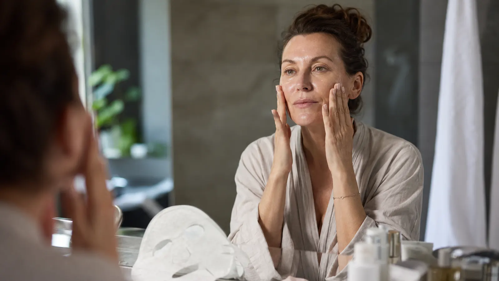 Woman applying moisturizer to freshly treated skin after a red light therapy session