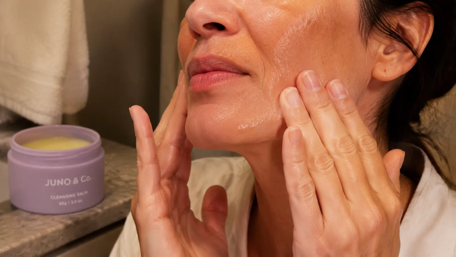 Close-up of dry hands massaging JUNO Clean 10 Cleansing Balm into dry, unwashed skin