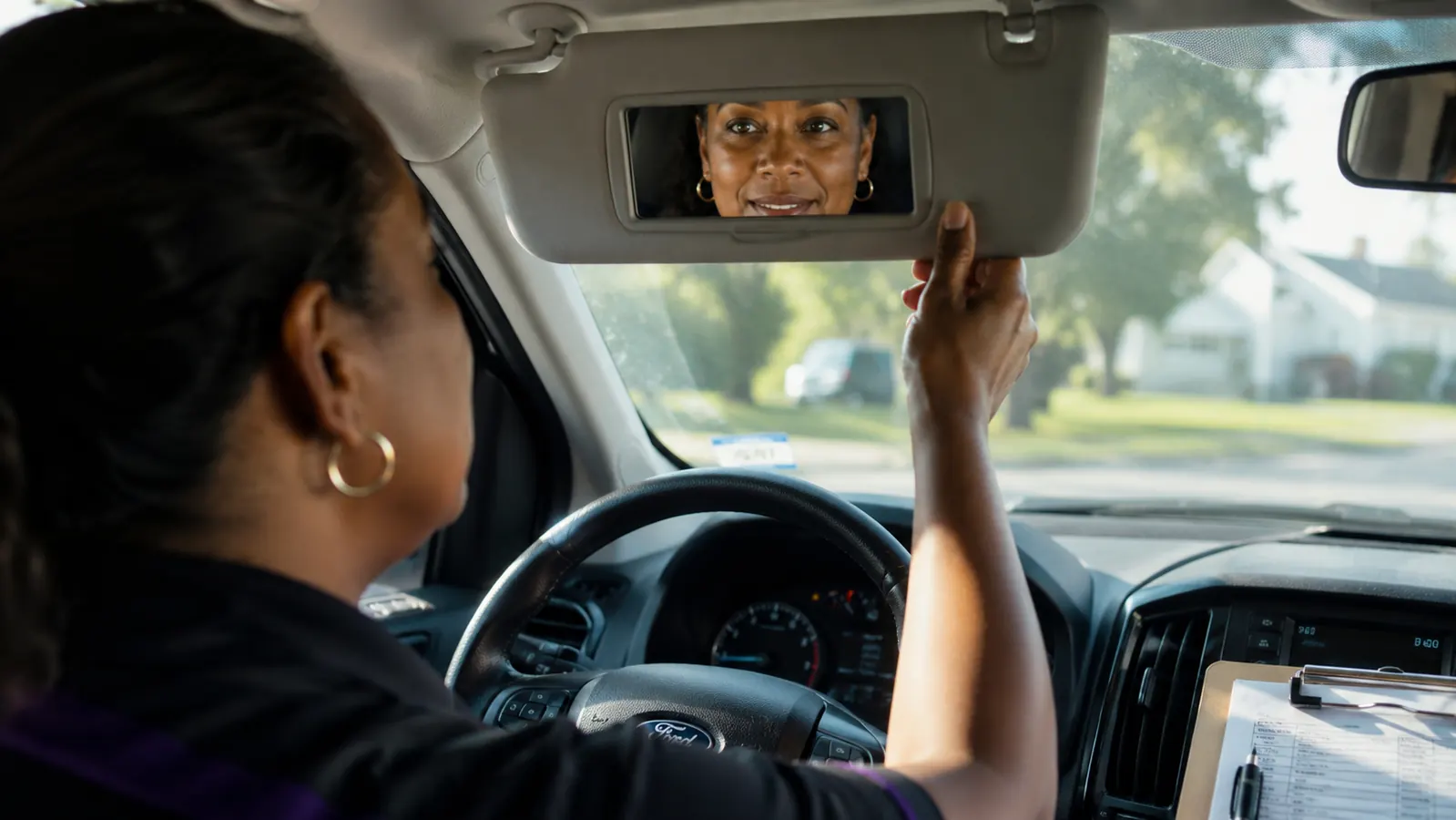 Woman with clearer, more even-toned skin checking her reflection in a car visor mirror in daylight